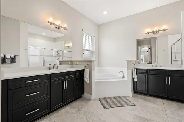 a spacious bathroom with a tub double sink and a mirror
