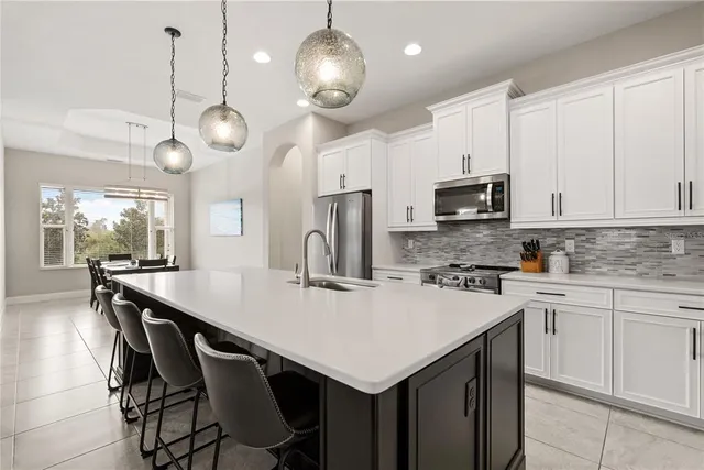 a kitchen with stainless steel appliances a table chairs sink and cabinets