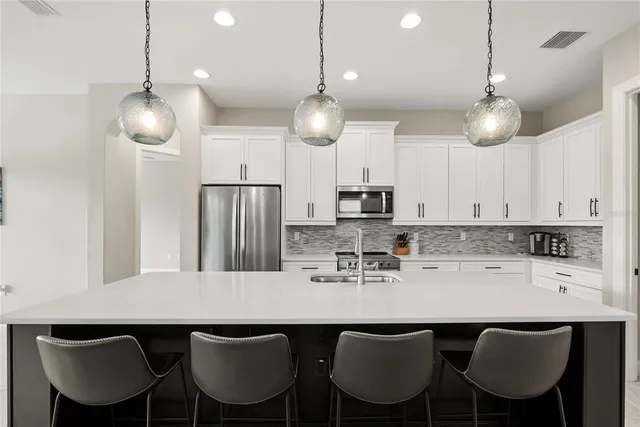 a kitchen with stainless steel appliances a dining table chairs and wooden cabinets