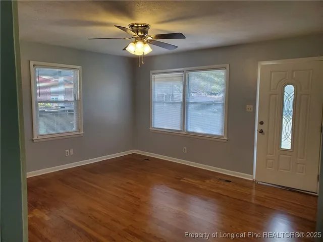 a view of an empty room with wooden floor and a window