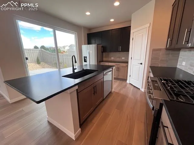 a kitchen with kitchen island granite countertop a stove a sink a refrigerator wooden floor and cabinets