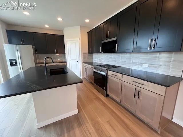 a kitchen with stainless steel appliances granite countertop a sink a stove top oven a counter space and cabinets