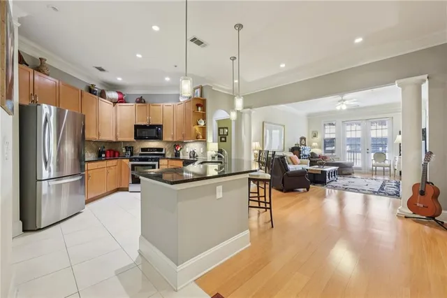 a kitchen with stainless steel appliances granite countertop a refrigerator a oven a sink a stove and white cabinets with wooden floor