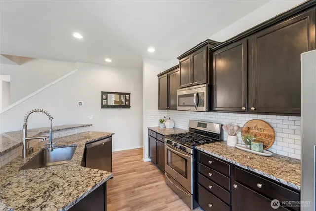 a kitchen with kitchen island wooden floors appliances and cabinets