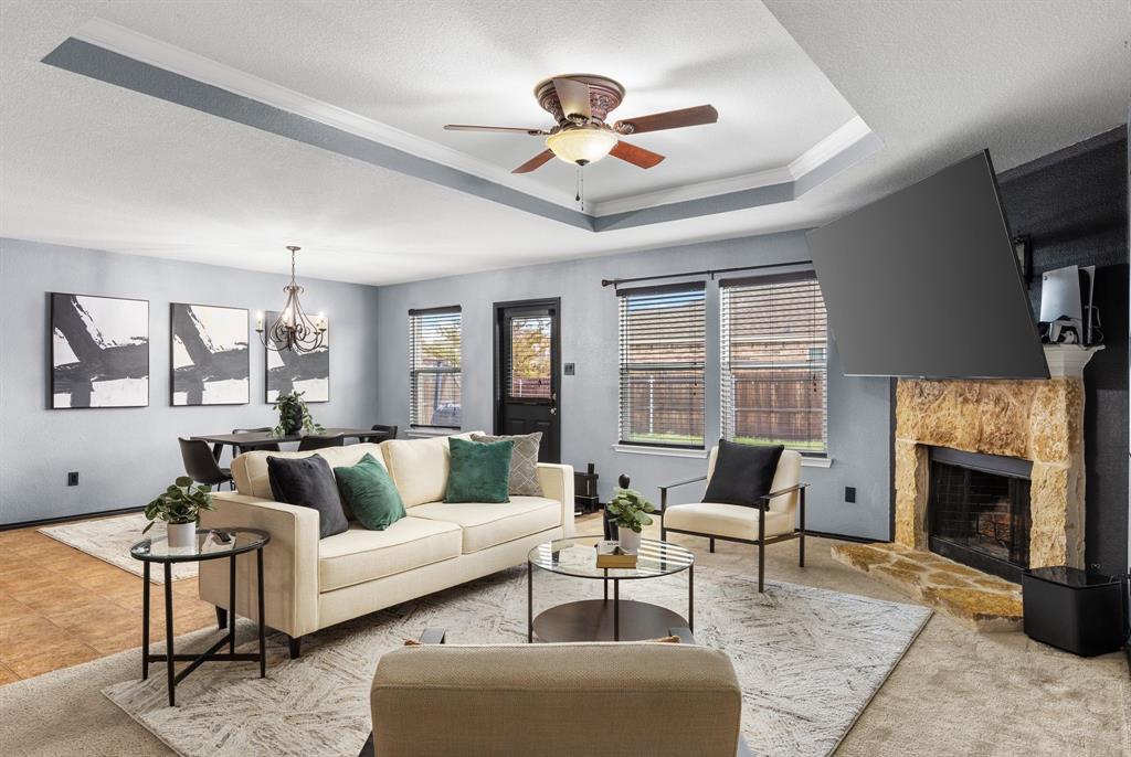1014 Rio Frio Drive Forney, TX 75126 - Photo 9 of 19 Living area with a raised ceiling, a chandelier, a fireplace with raised hearth, a ceiling fan, and ornamental molding