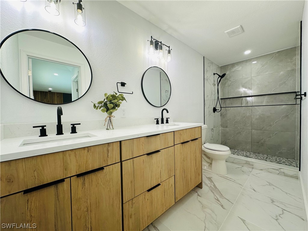 2926 Holly Road Fort Myers, FL 33901 - Photo 36 of 47 a bathroom with a double vanity sink mirror and toilet