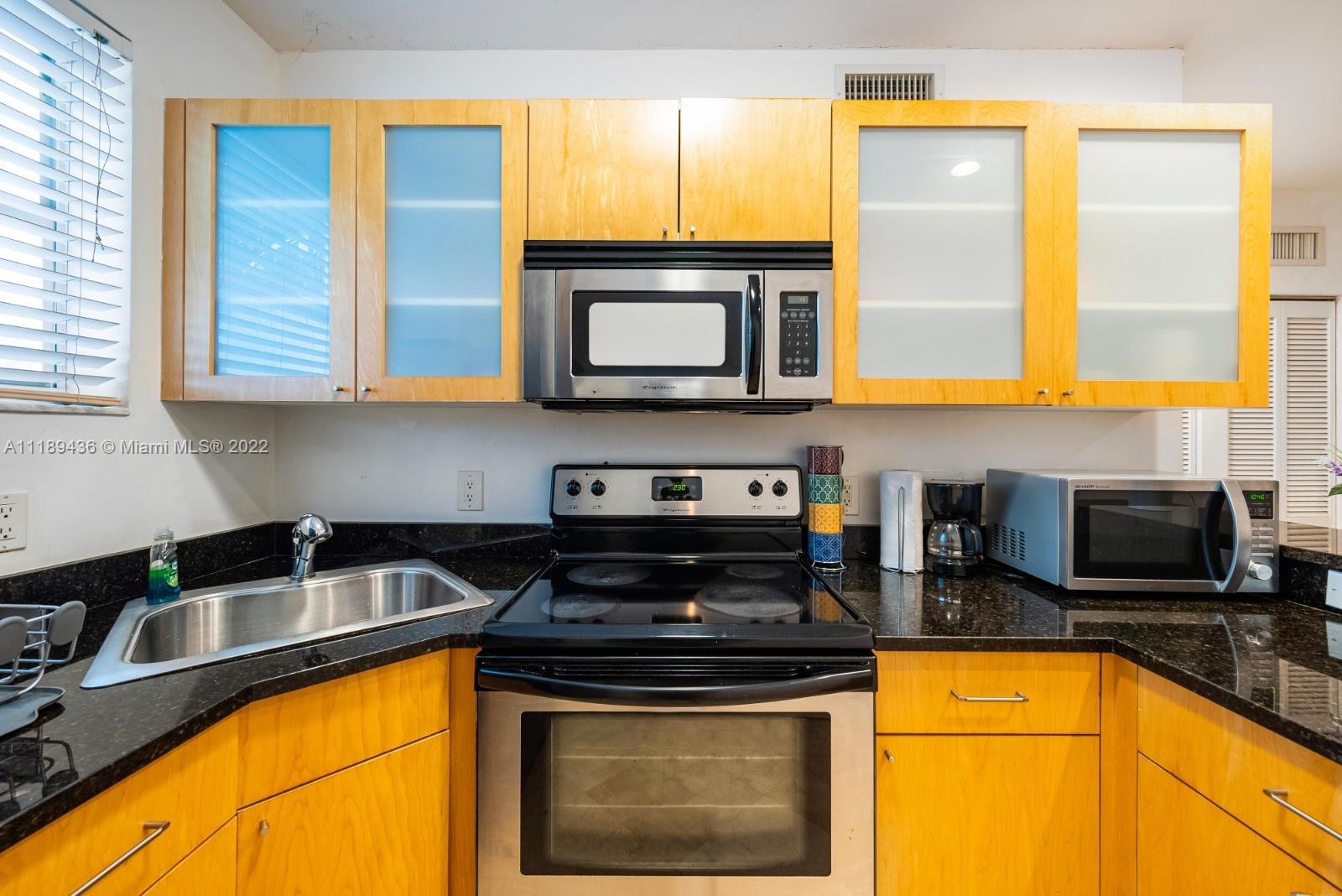 751 Collins Avenue, Unit 6 Miami Beach, FL 33139 - Photo 2 of 15 a kitchen with stainless steel appliances granite countertop a stove a sink and a microwave