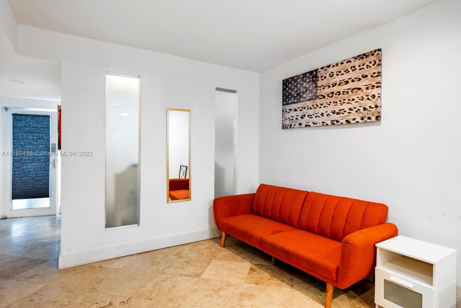 751 Collins Avenue, Unit 6 Miami Beach, FL 33139 - Photo 6 of 15 a blue couch sitting in a living room with a rug