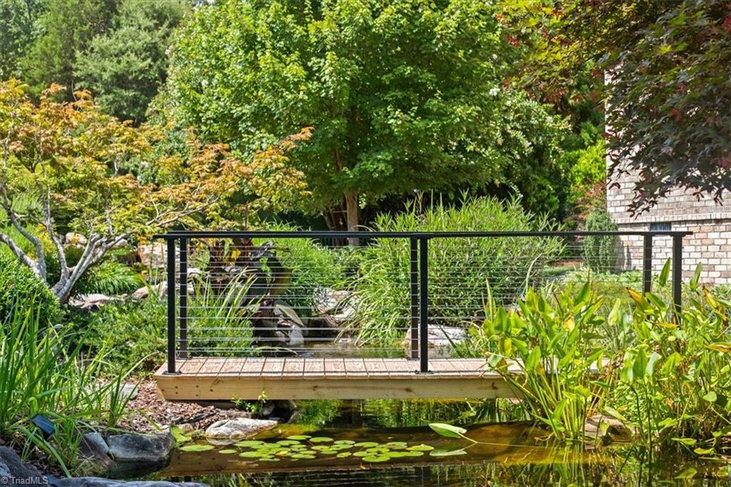 8400 Parkchester Place Oak Ridge, NC 27310 - Photo 32 of 49 bridge leading towards firepit stone patio area and large private pond