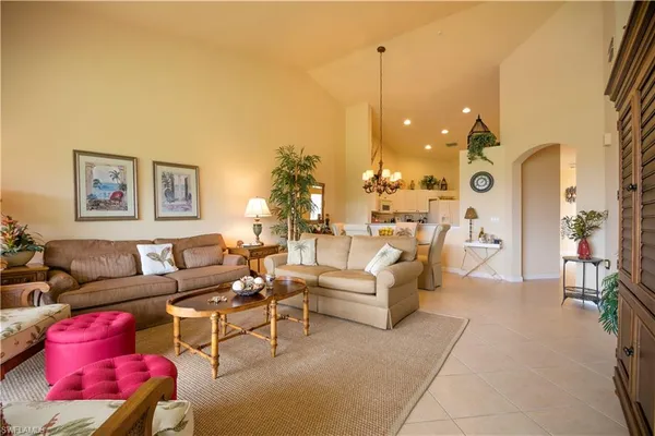 a living room with furniture kitchen view and a chandelier