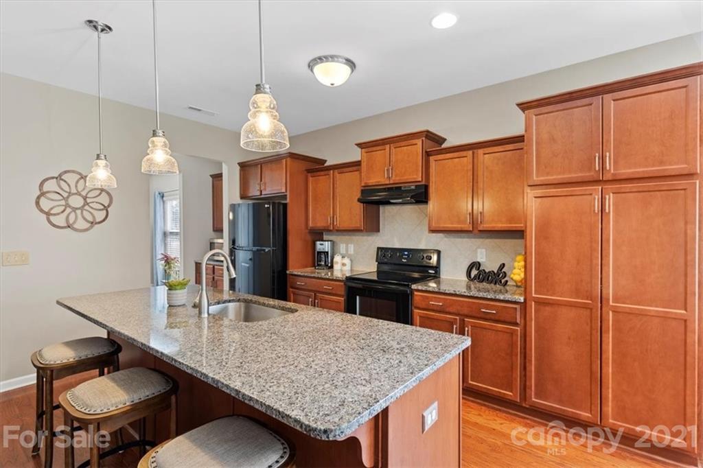 8098 Bryson Road Indian Land, SC 29707 - Photo 10 of 30 a kitchen with granite countertop a table chairs stove and cabinets