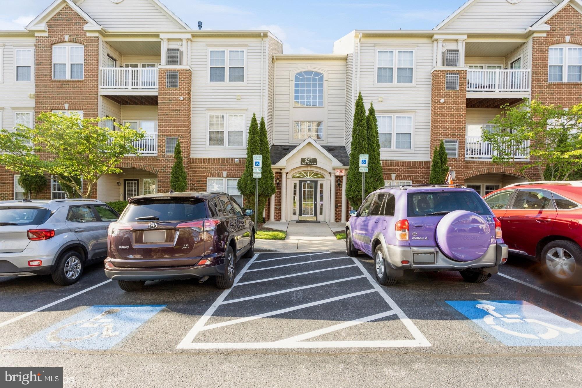 a front view of a residential apartment building with cars parked