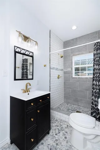 a bathroom with a double vanity sink toilet mirror and shower