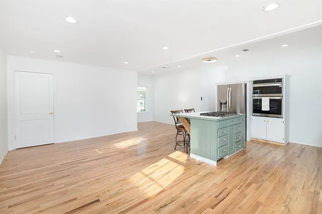 a large white kitchen with wooden floors and stainless steel appliances