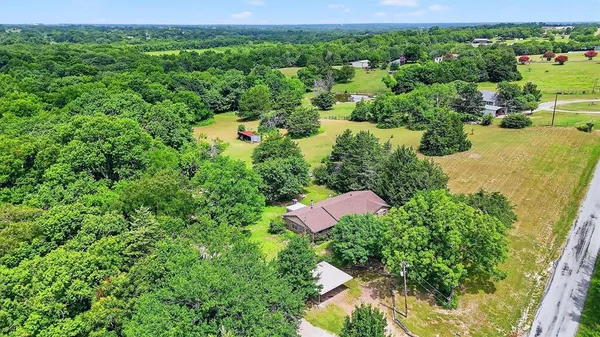 an aerial view of residential house with outdoor space and trees all around