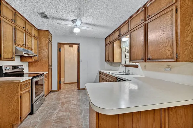 a kitchen with stainless steel appliances granite countertop a sink a stove and a refrigerator