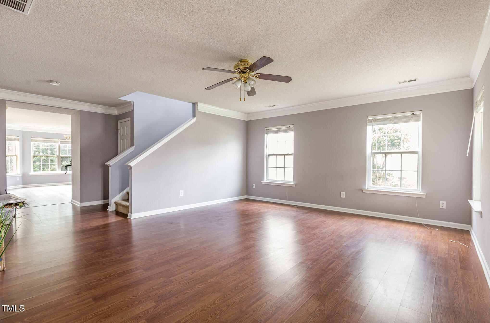 2640 Quarry Springs Road Raleigh, NC 27610 - Photo 3 of 31 an empty room with wooden floor ceiling fan and windows