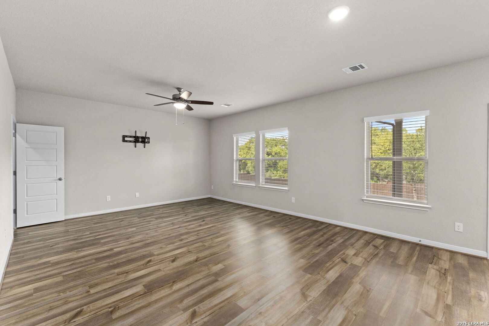 12221 Icon Ridge San Antonio, TX 78253 - Photo 9 of 46 an empty room with wooden floor chandelier fan and windows
