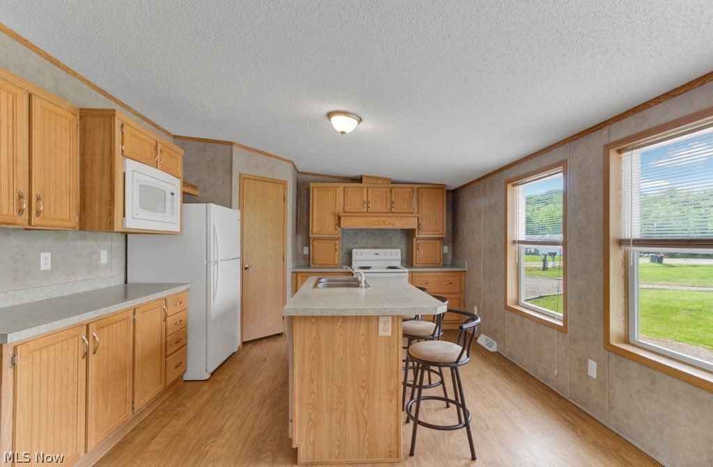 1110 Fort Road Southwest Dellroy, OH 44620 - Photo 5 of 50 Kitchen featuring light hardwood / wood-style floors, a center island with sink, crown molding, sink, and white appliances