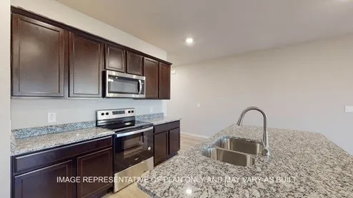 a kitchen with granite countertop a stove a sink and a microwave