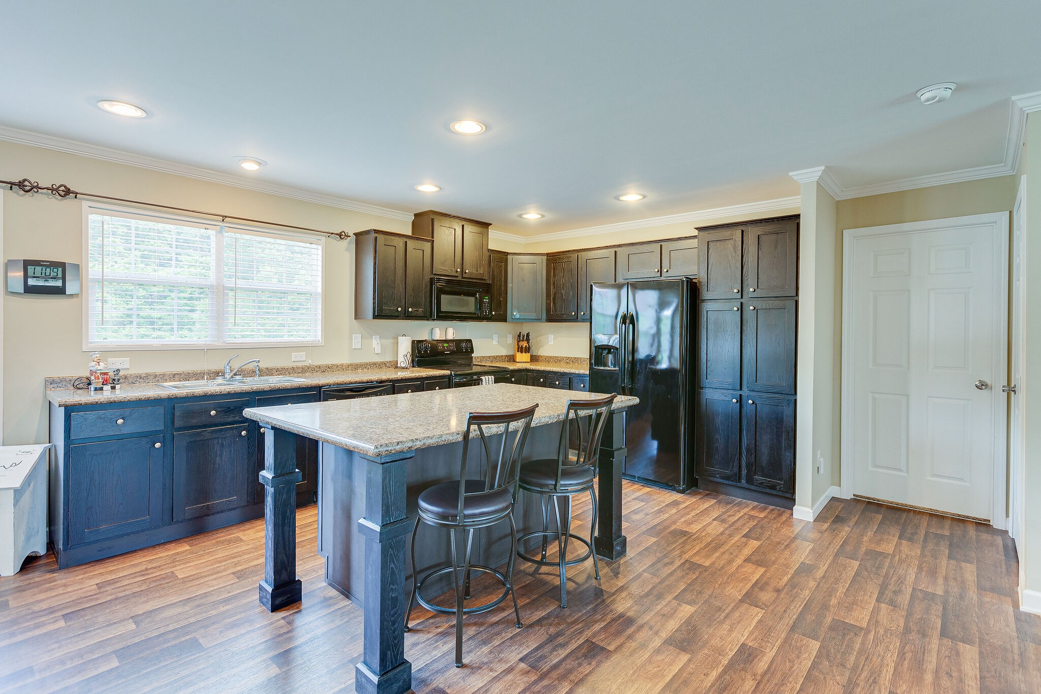 3349 Mahlon Moore Road Spring Hill, TN 37174 - Photo 11 of 28 a kitchen with stainless steel appliances granite countertop a refrigerator a sink dishwasher a stove and a dining table with wooden floor