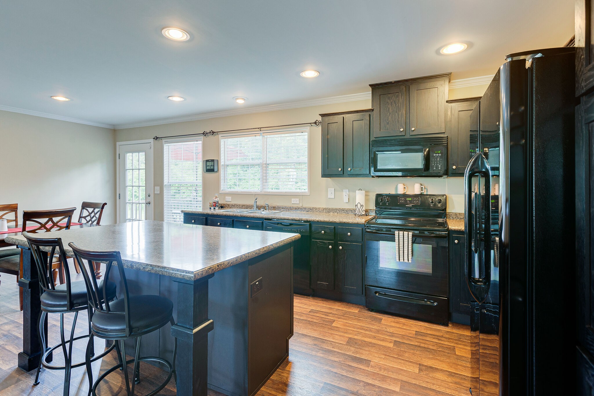 3349 Mahlon Moore Road Spring Hill, TN 37174 - Photo 12 of 28 a kitchen with stainless steel appliances granite countertop a refrigerator a stove a sink dishwasher a dining table and chairs with wooden floor