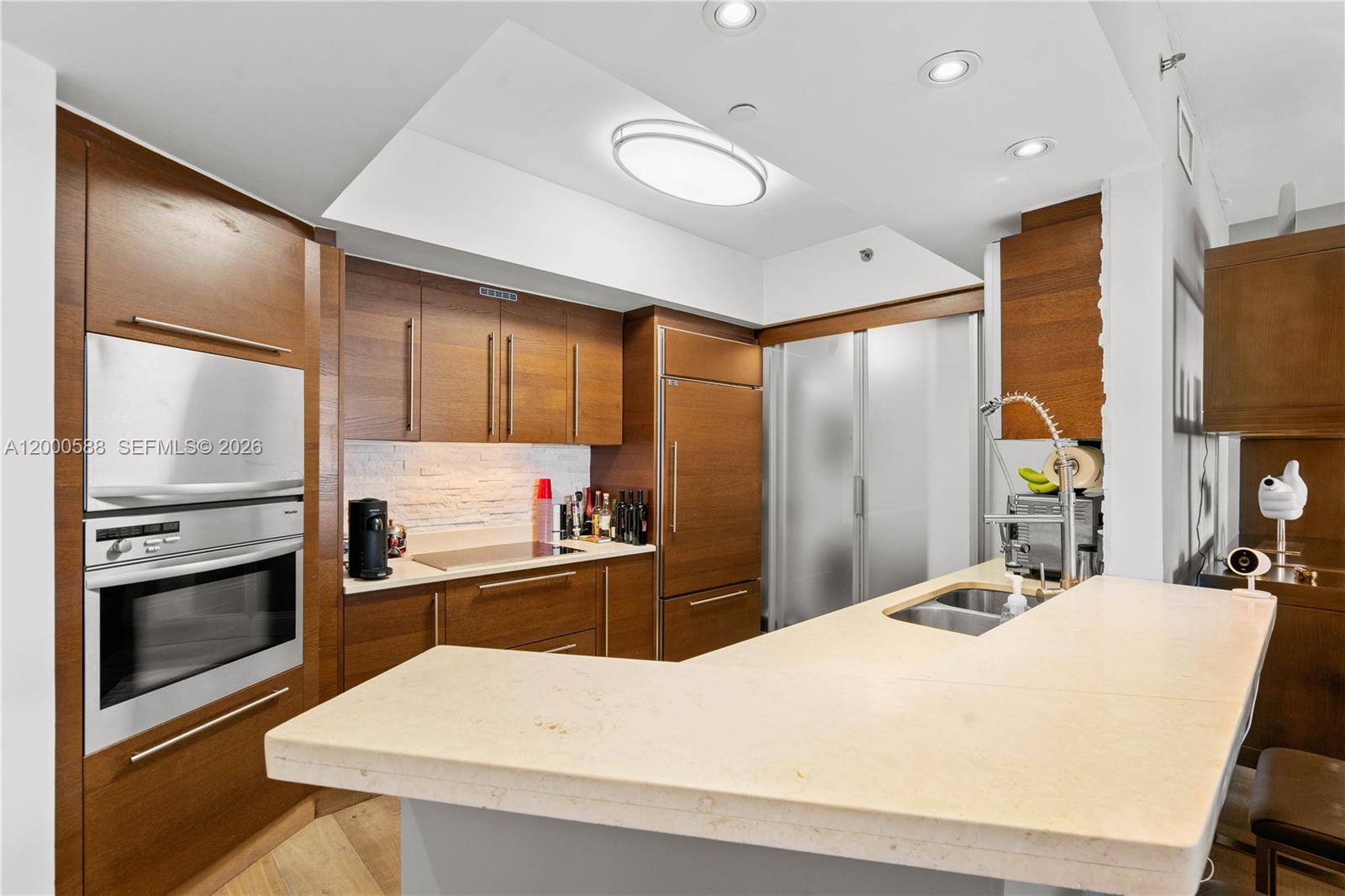 450 Alton Road, Unit 806 Miami Beach, FL 33139 - Photo 6 of 23 a kitchen with stainless steel appliances kitchen island granite countertop a refrigerator a stove and a sink with wooden floor