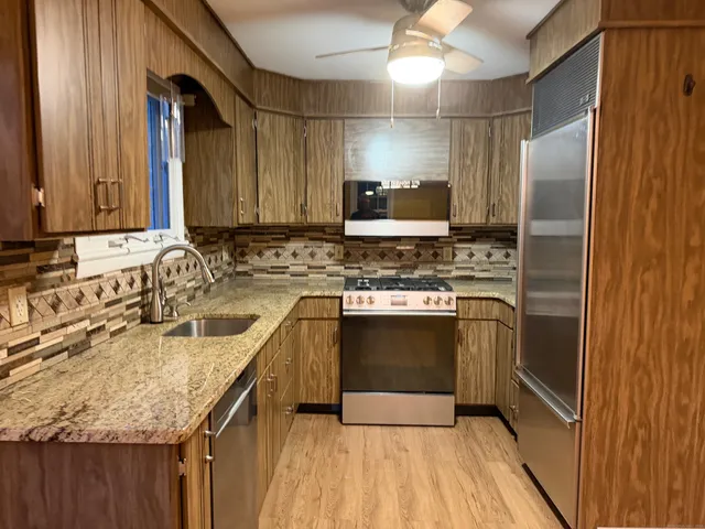 a kitchen with stainless steel appliances granite countertop a sink stove and refrigerator