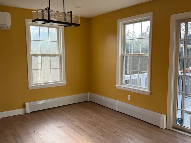 a view of an empty room with a window and wooden floor