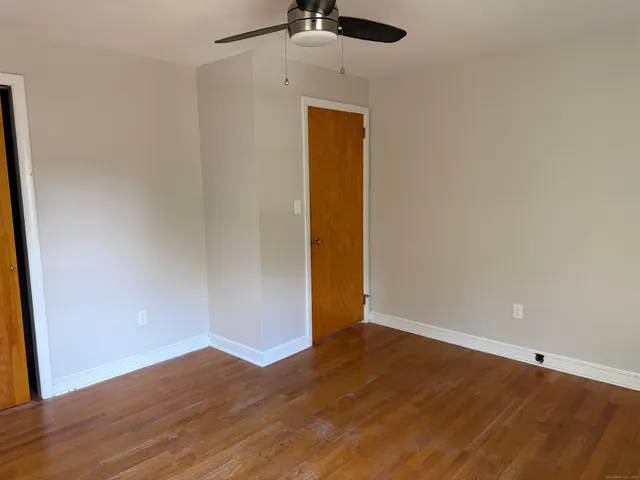an empty room with wooden floor and a ceiling fan