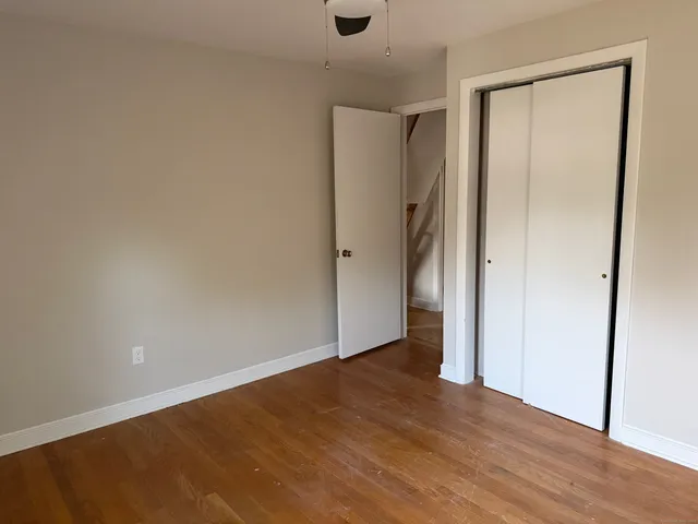 an empty room with wooden floor and a ceiling fan