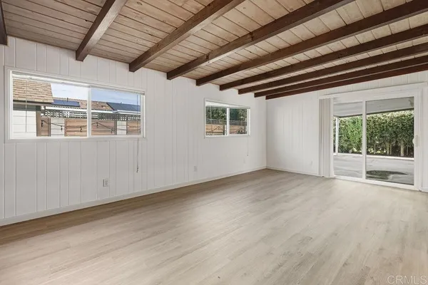 a view of an empty room with wooden floor and a fireplace