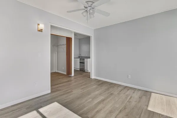 a view of an empty room with wooden floor and a window