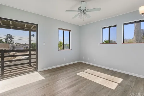 an empty room with wooden floor chandelier and windows