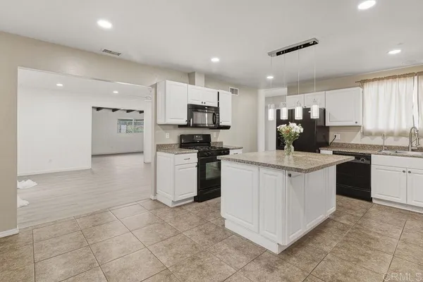 a kitchen with a stove a sink a microwave a refrigerator and white cabinets