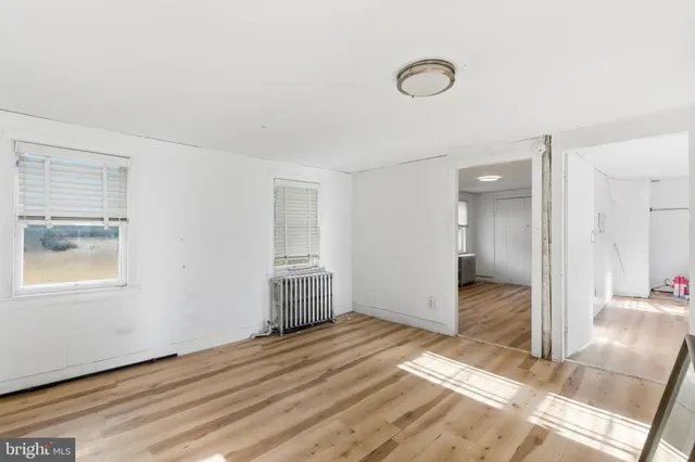 a view of a livingroom with wooden floor and a refrigerator