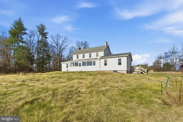 a view of a house with backyard and trees in the background