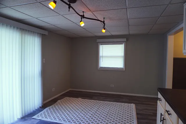 a view of an empty room with window and chandelier fan