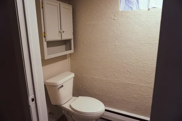 a white toilet sitting next to a wooden cabinet