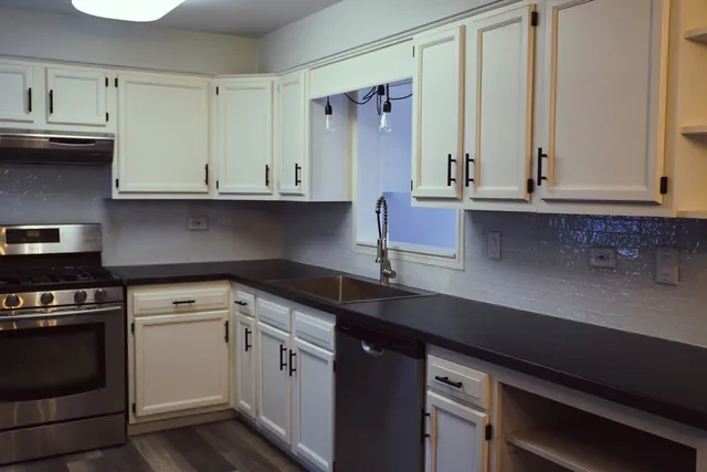 a kitchen with stainless steel appliances granite countertop a sink stove and cabinets