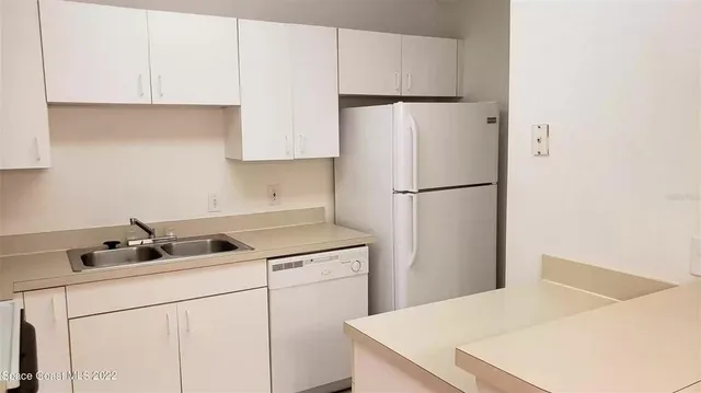 a kitchen with a refrigerator a stove top oven and white cabinets