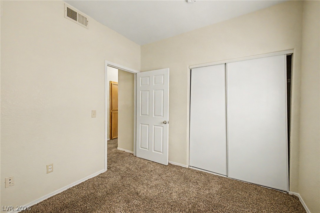 4730 East Craig Road, Unit 1091 Las Vegas, NV 89115 - Photo 19 of 23 Plush carpeting anchors this bedroom containing integrated sliding closet doors and a neutral color palette.