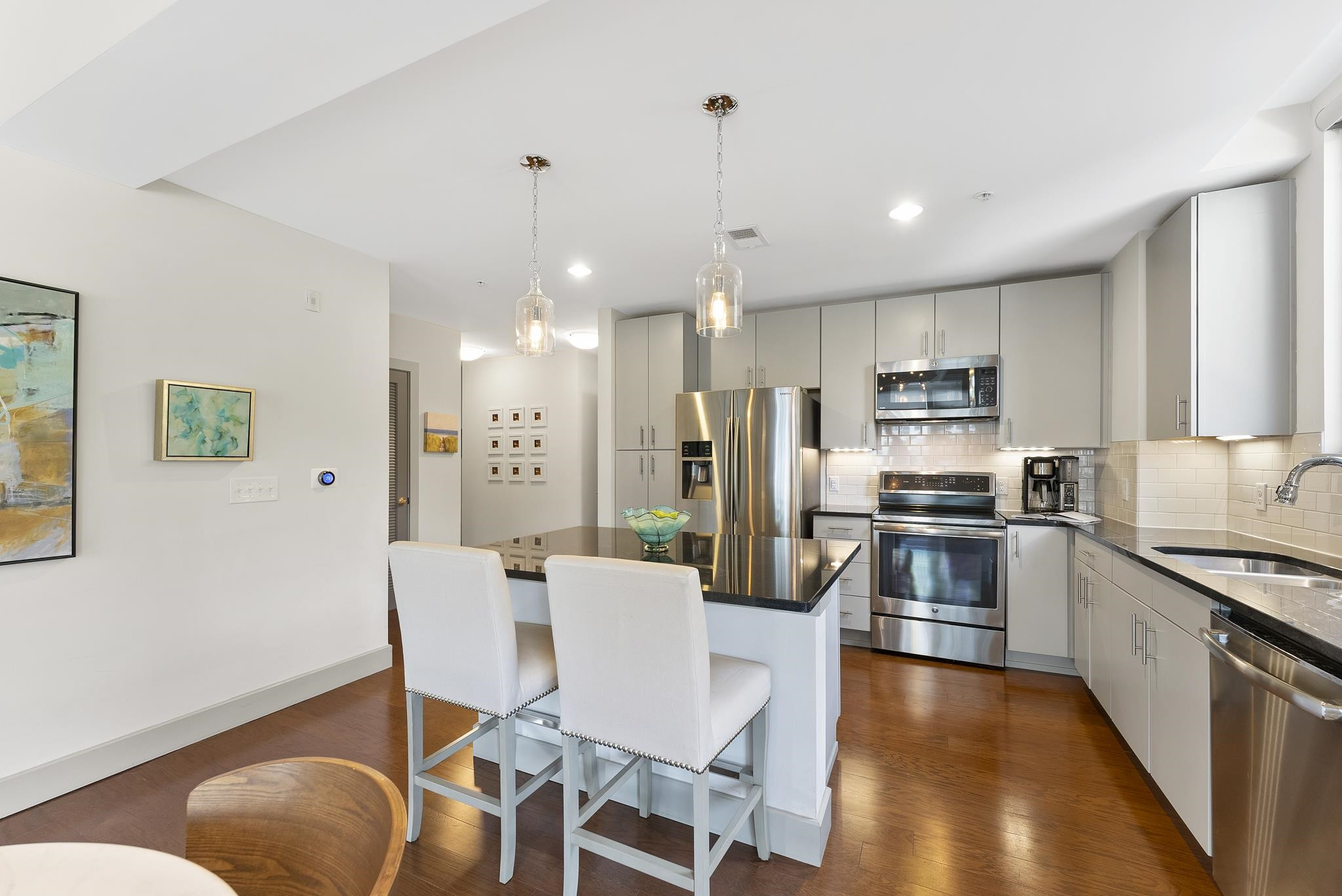 1300 St Marys Street, Unit 306 Raleigh, NC 27605 - Photo 4 of 30 a kitchen with stainless steel appliances kitchen island granite countertop a refrigerator a stove a sink dishwasher a dining table and chairs with wooden floor