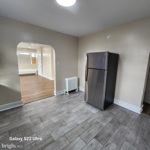 a view of a refrigerator in kitchen and an empty room