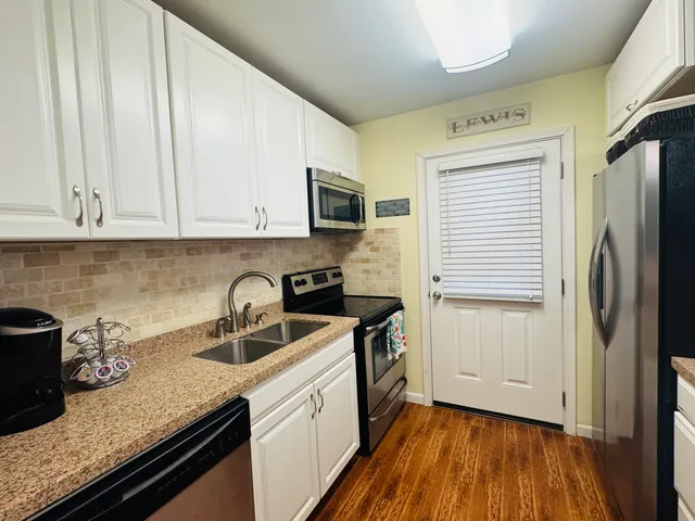 a kitchen with granite countertop a sink a stove and refrigerator