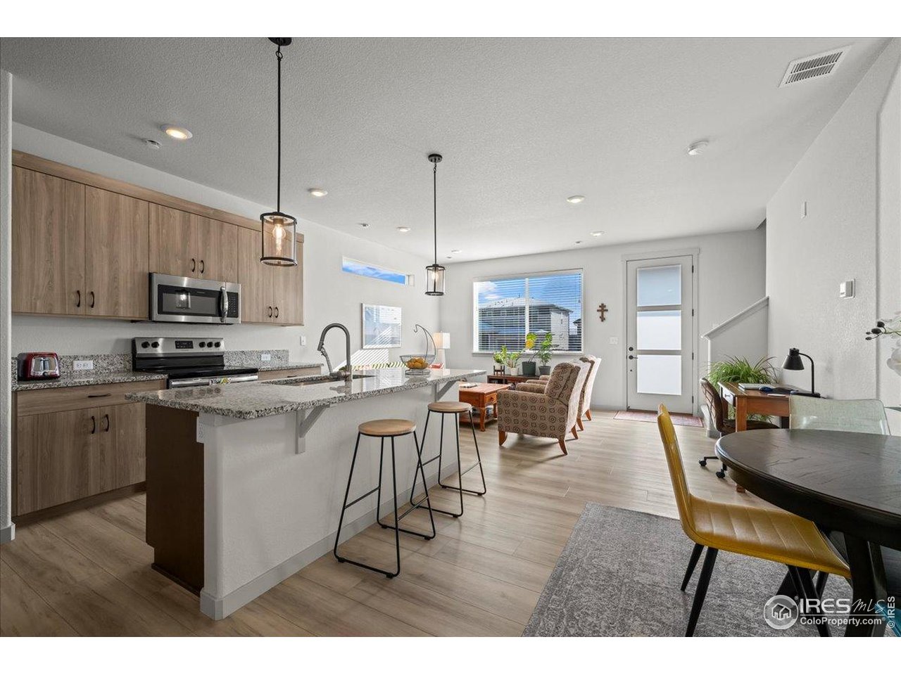 1088 Blue Bell Road Berthoud, CO 80513 - Photo 13 of 33 a open dining room with stainless steel appliances kitchen island granite countertop a table chairs and a refrigerator