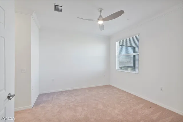 an empty room with a chandelier fan and windows