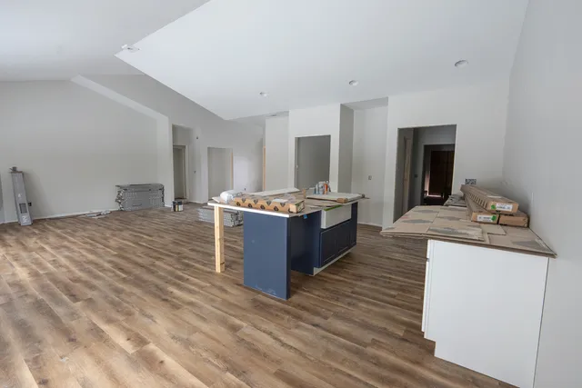 a large room with kitchen island a sink a stove and a wooden floors