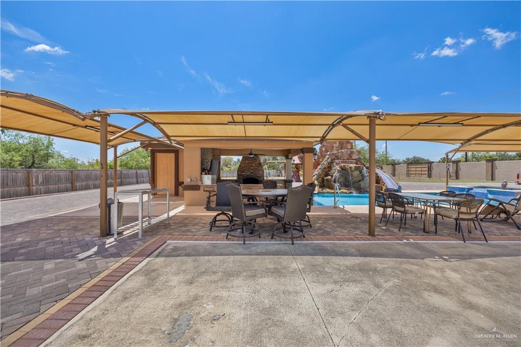 800 East Mile 3 Road Mission, TX 78573 - Photo 45 of 45 Fenced backyard featuring outdoor dining space, an outdoor pool, a patio, an outdoor kitchen, and a ceiling fan