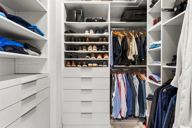 a view of walk in closet with clothes and shoes